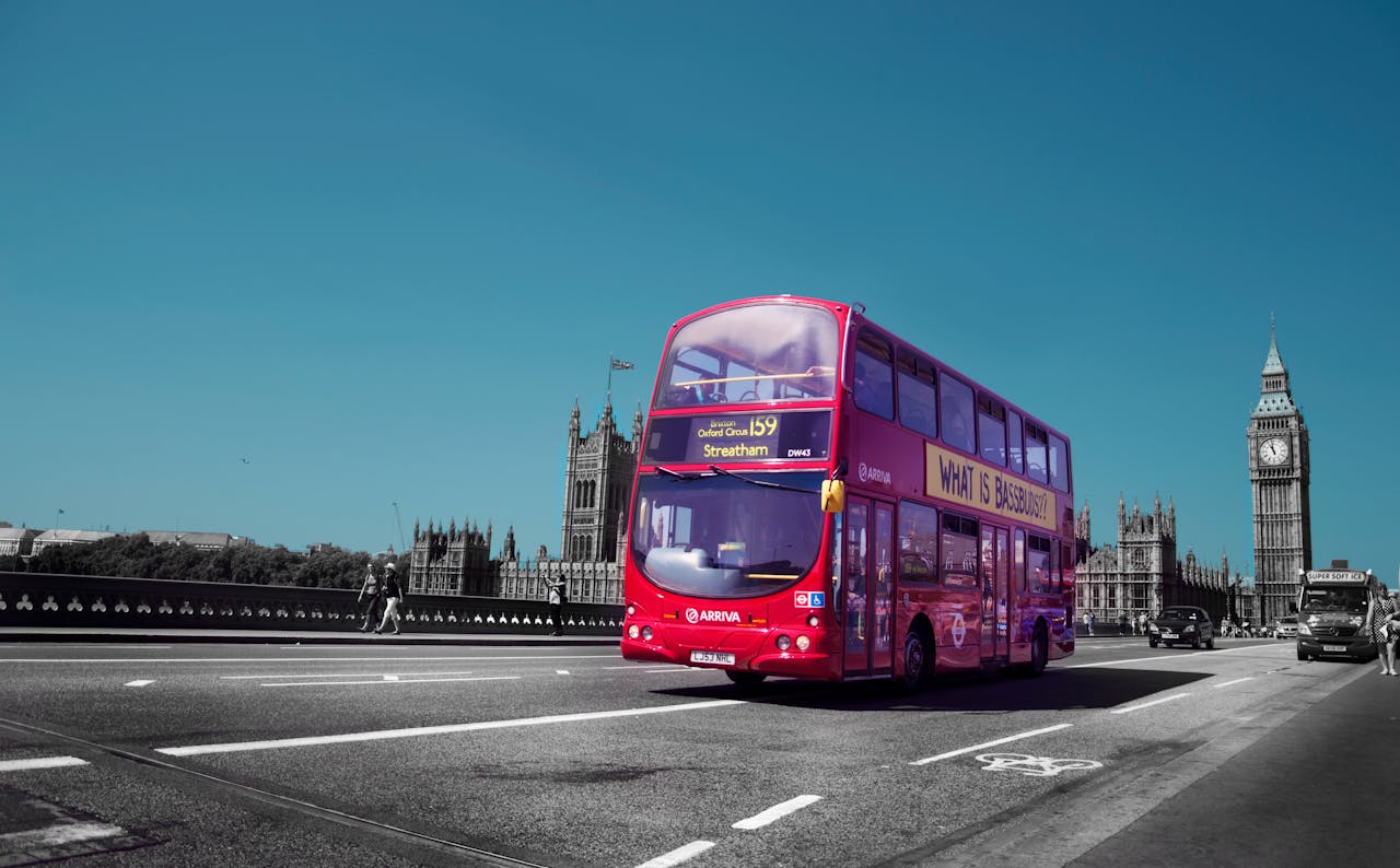 Classic London scene featuring a red double-decker bus passing by Big Ben on a clear day.